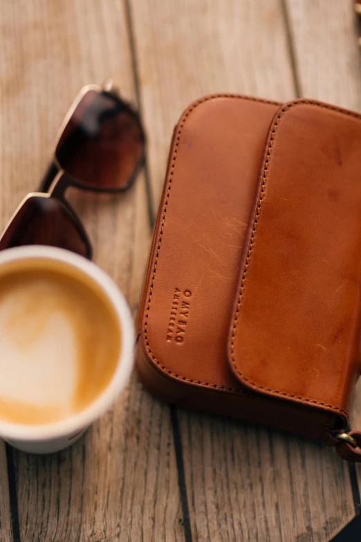 there is a cup of coffee on the table next to some sunglasses