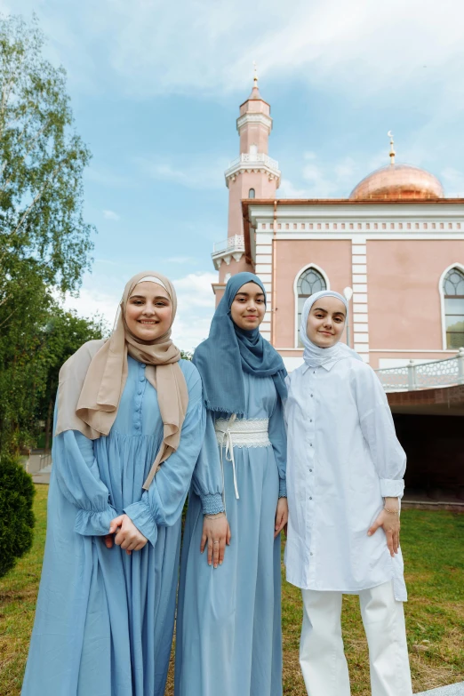 three women wearing hijabs standing in front of a building