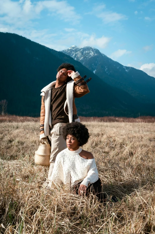 two people sitting on the grass in the mountains