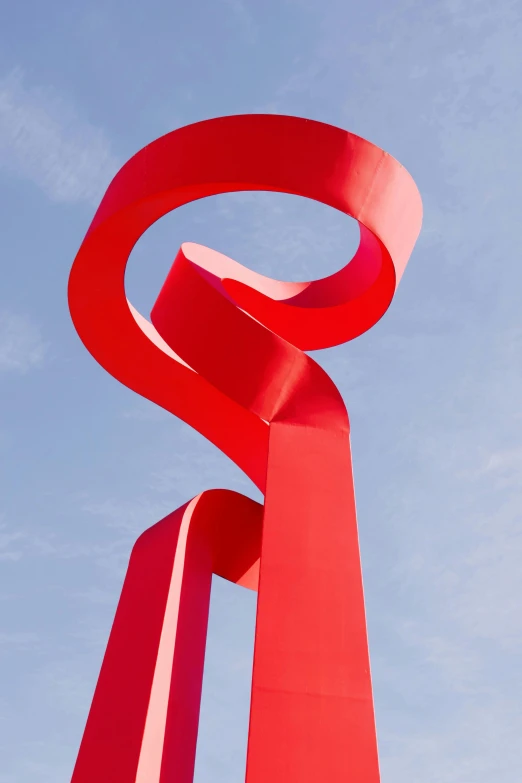 a red sculpture stands beneath a blue sky