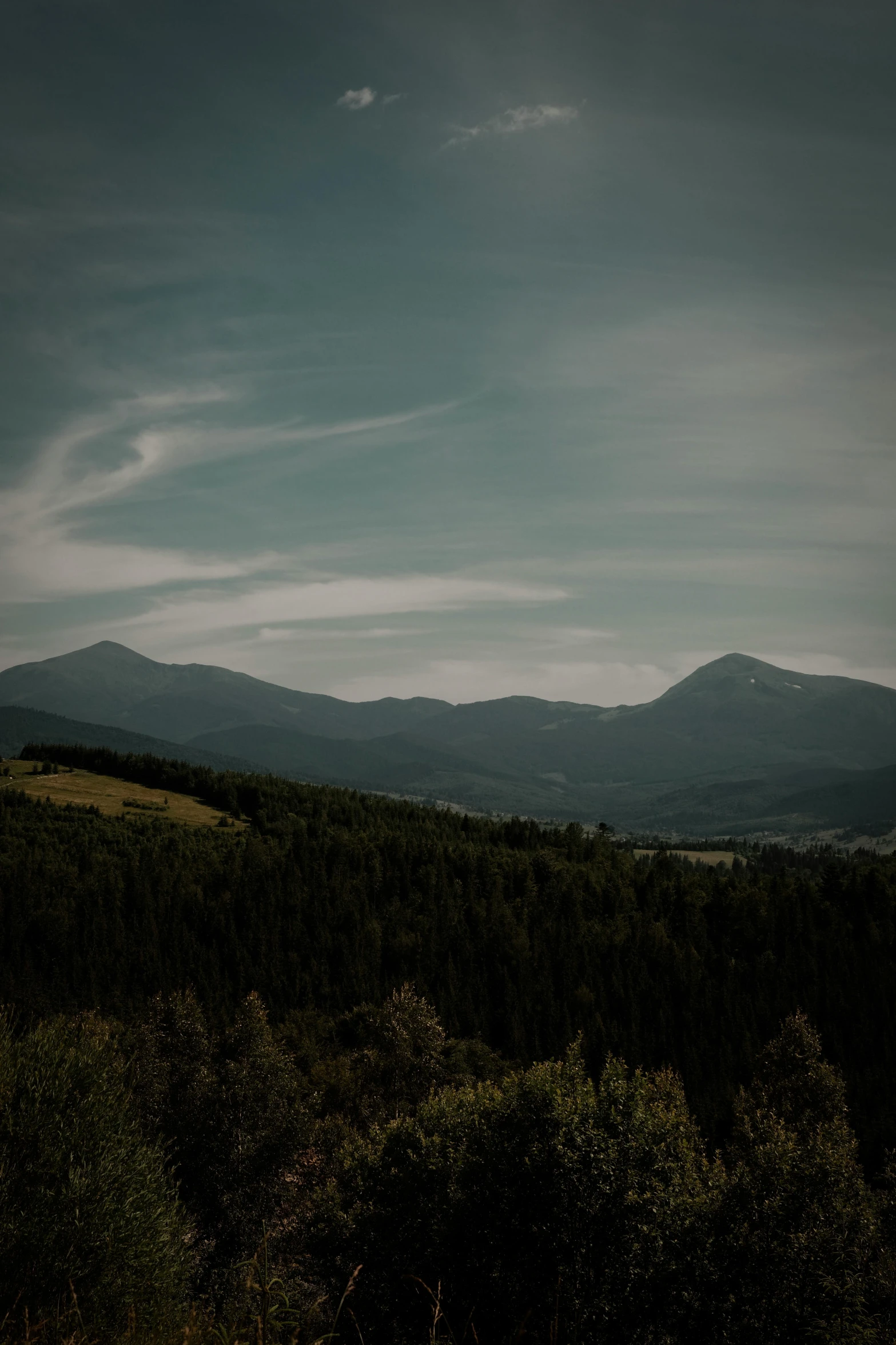 a view from the top of a mountain, with hills in the distance