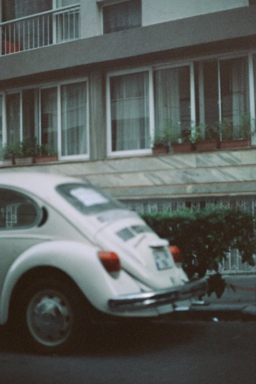 white vintage beetle with flat tire is parked on the side of the road