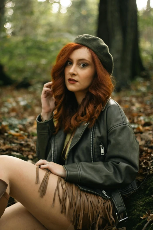 a woman with red hair sitting in the woods