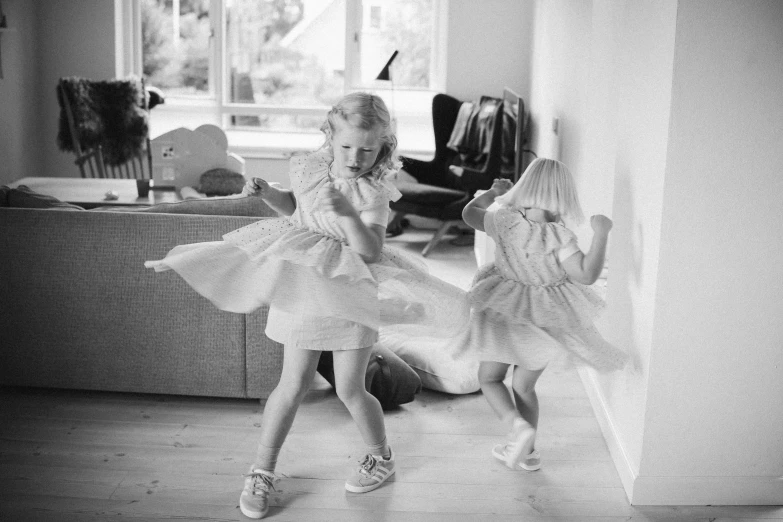 two little girls are dressed in dresses in a room