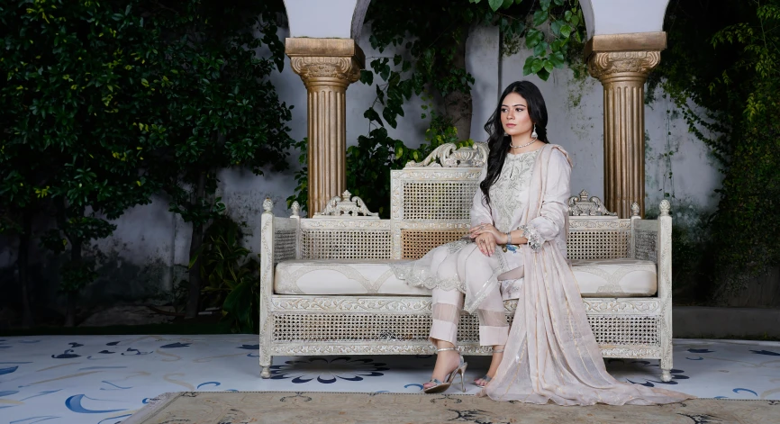 a lady sitting on a white chair that has a fancy pattern