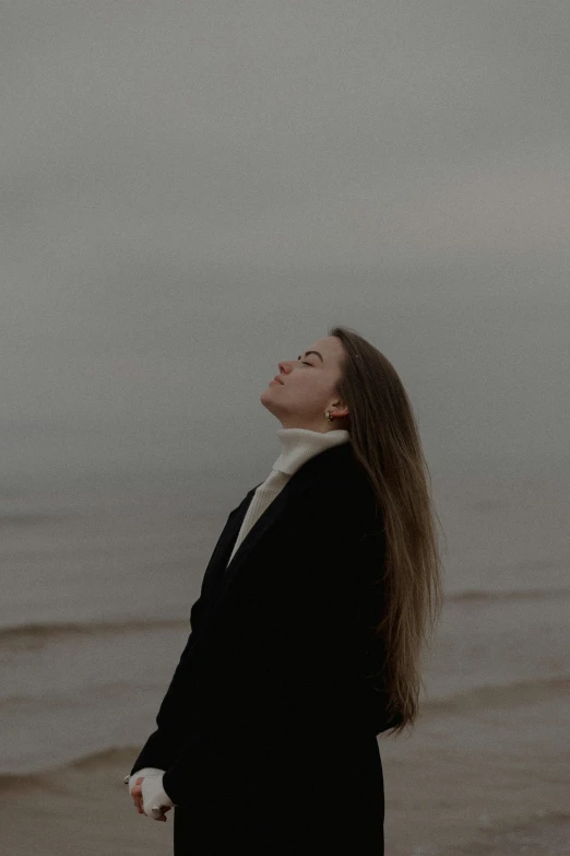 a woman with her eyes closed and standing in front of the water