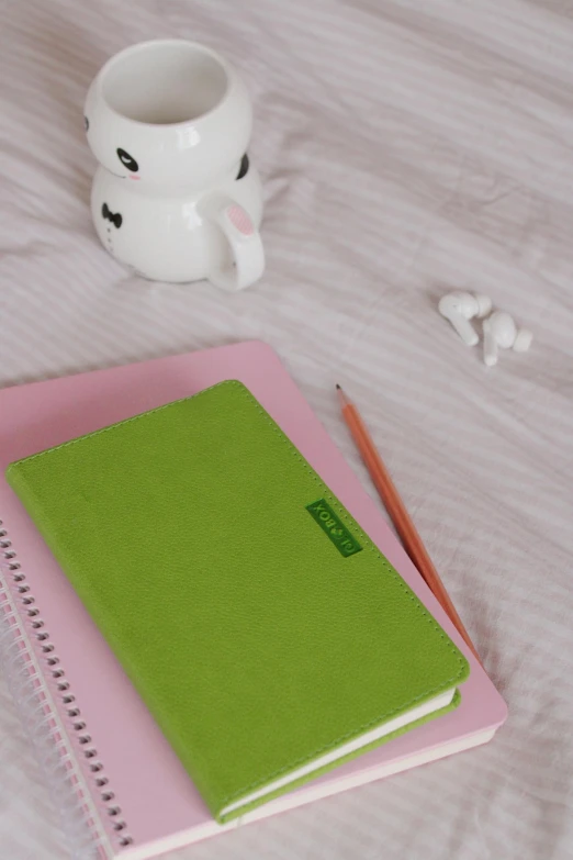 a close up of a notebook and pencil near a tea cup