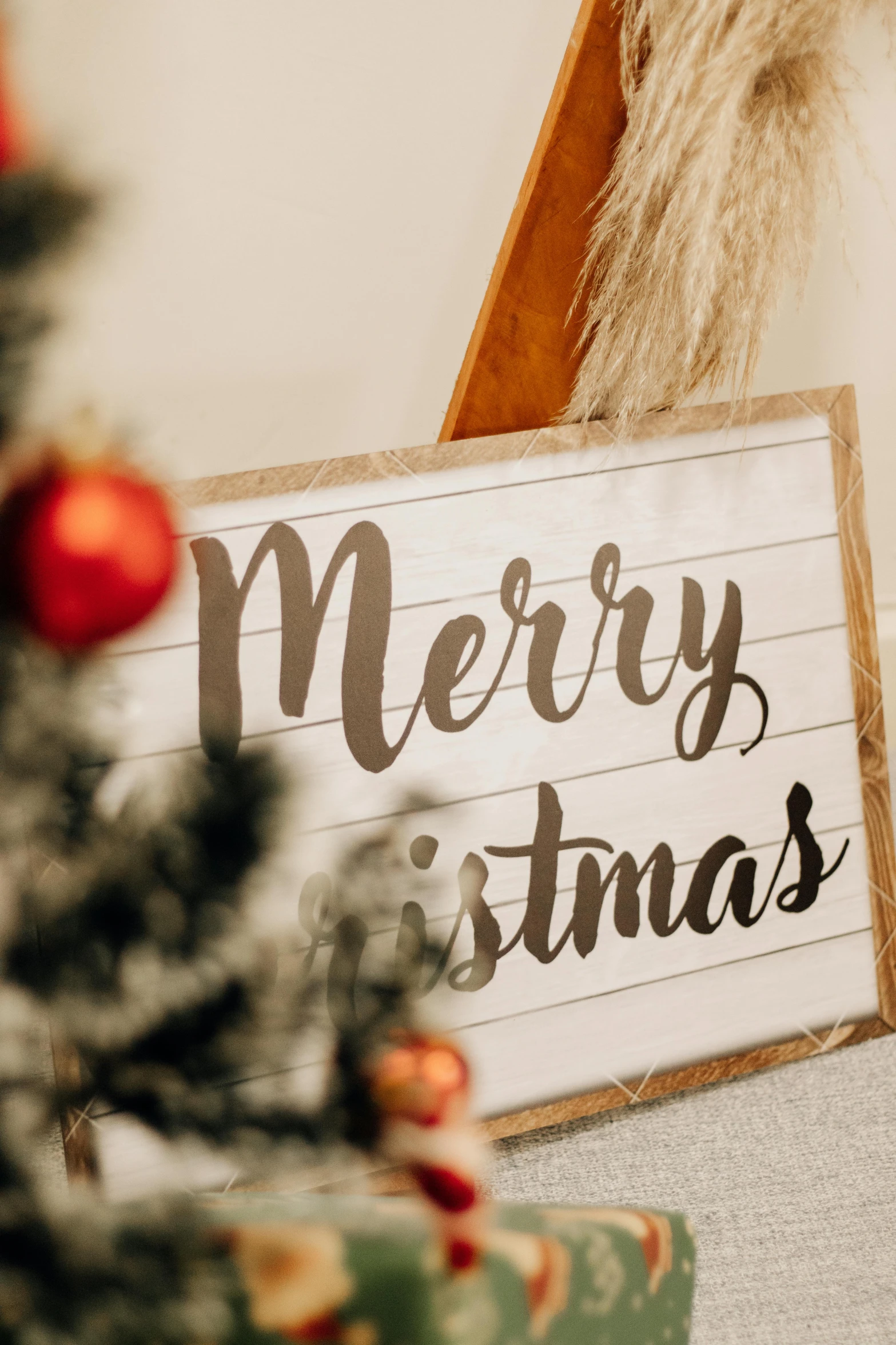 a merry christmas wooden sign in front of a christmas tree