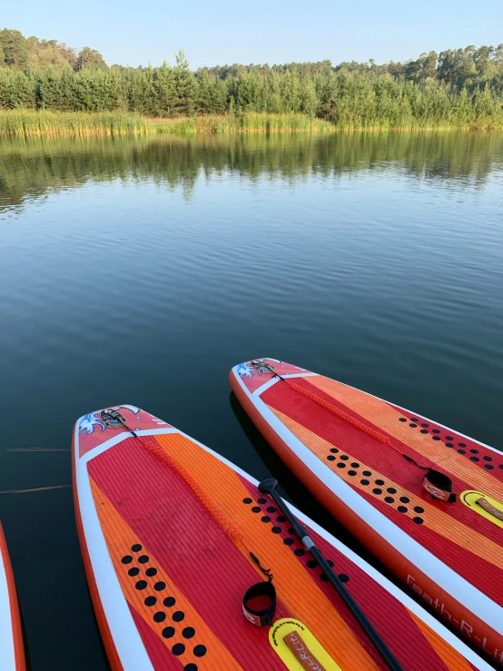 two rows of orange and white kayaks in water