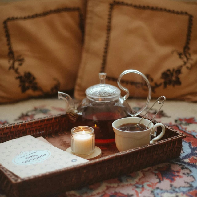 a tea tray with a candle on a couch next to a book