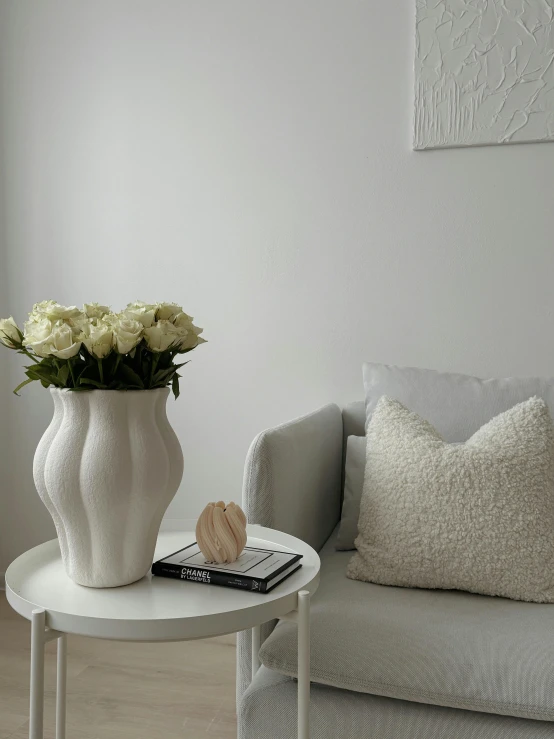 a living room area with flowers and a grey couch