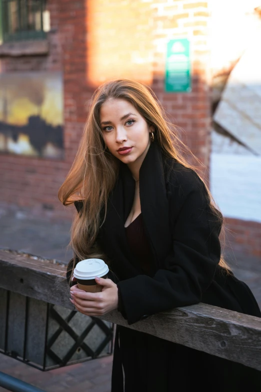 the woman is sitting on the wooden bench with her long hair blowing in the wind