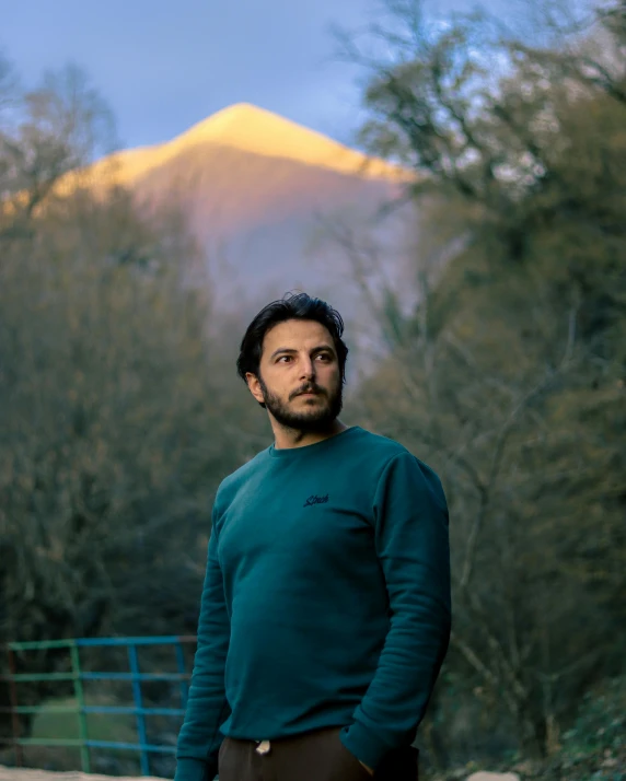 a man in green sweater standing near a fence