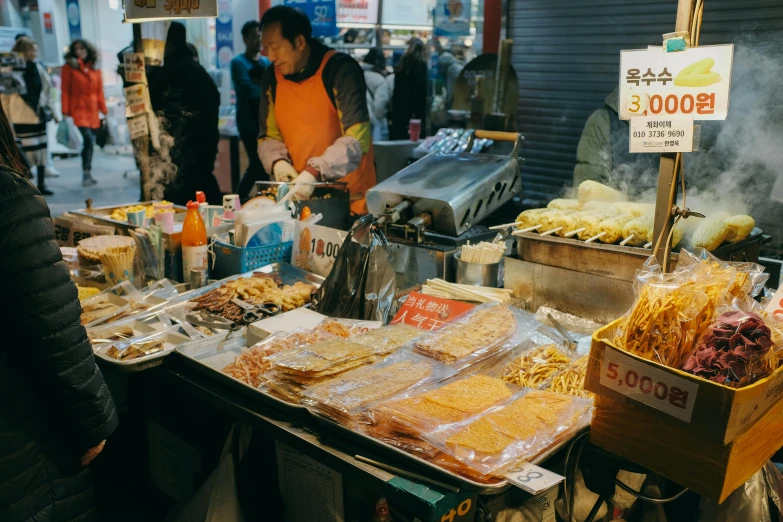 a street vendor stands near food items in a food market