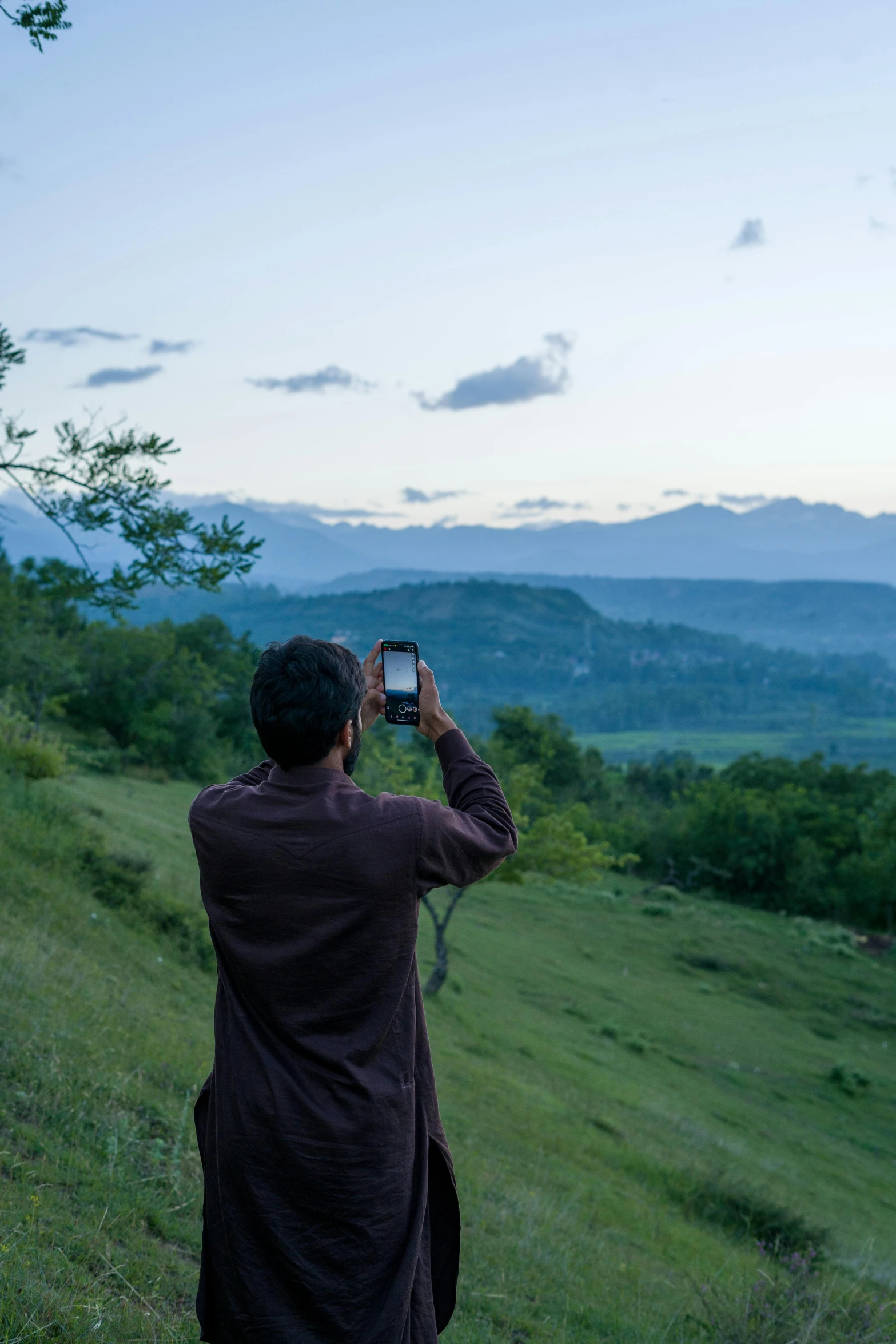 a man on top of a hill taking pictures of mountains