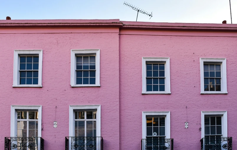 pink house with balcony and balcony railings and windows