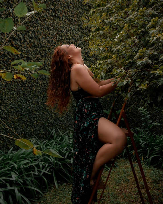 a woman wearing a dress is leaning on a ladder