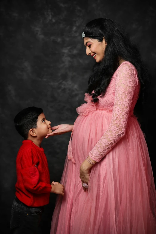 a woman in a pink dress feeding a boy