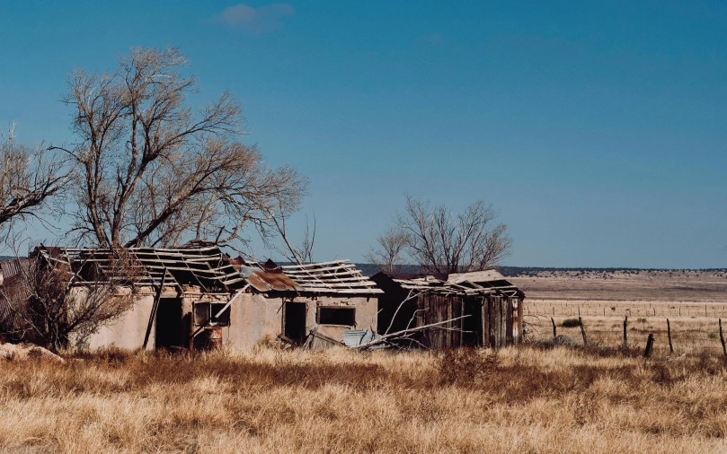 a ruined house on the side of a road in a field