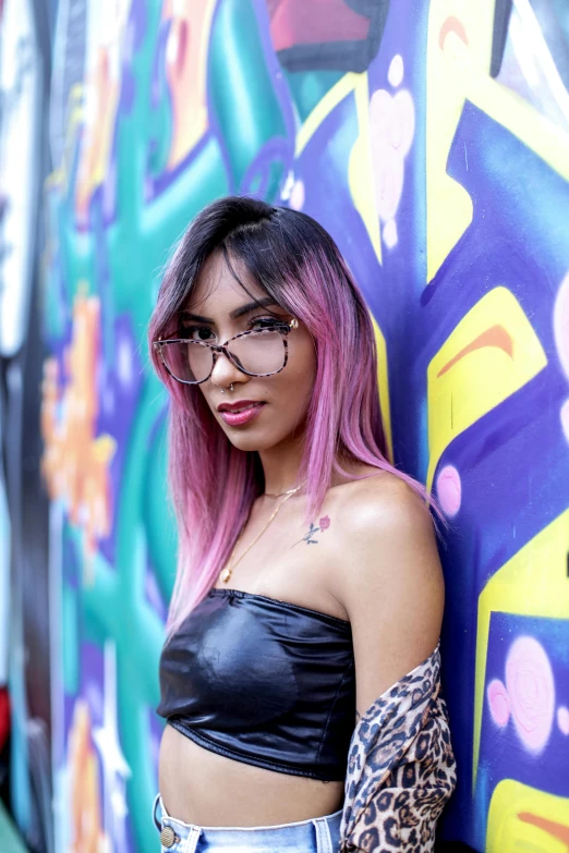 a woman with pink hair is standing in front of graffiti