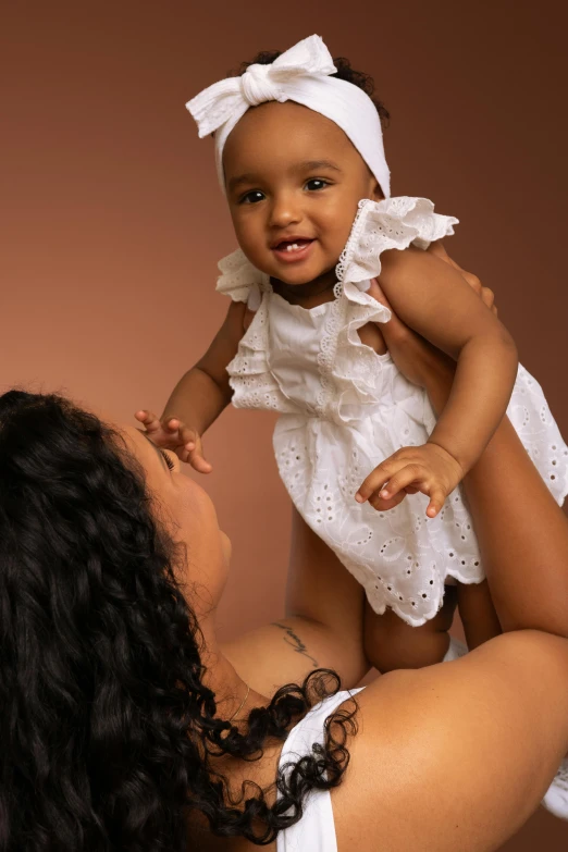 a smiling child with a dress on holding up a woman's chest