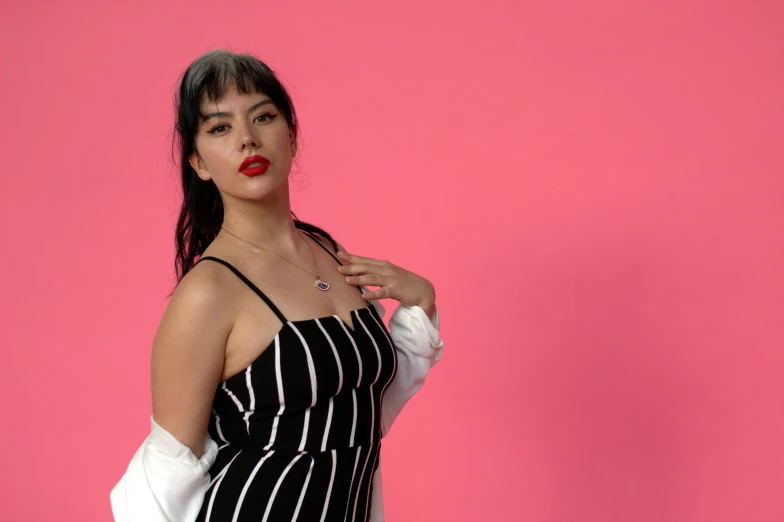 a young woman poses for a po against a pink background