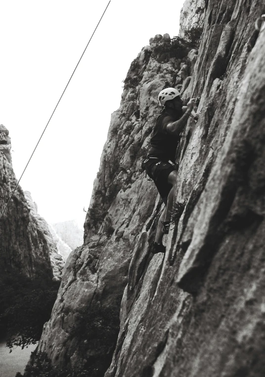 a man climbing on a rock wall in black and white