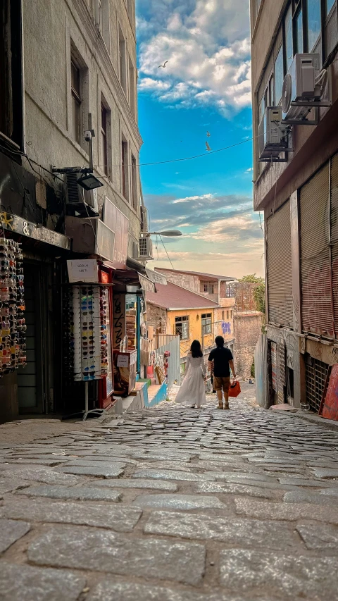 a couple walking down an alley lined with tall buildings