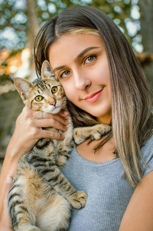 a woman smiles as she holds a cute cat