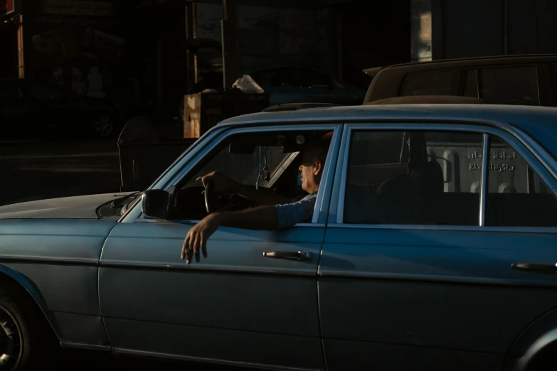 a person leaning out the window of a blue car on the street