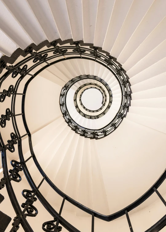 a white spiral staircase with black hand rails