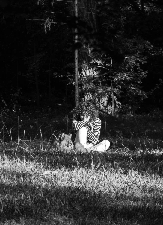 a person sits on the ground in front of some grass