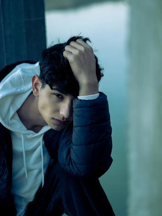 a young man holding his head while he stands