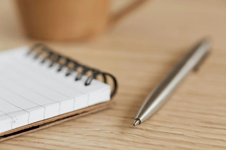 a note pad, pen and paper resting on a table