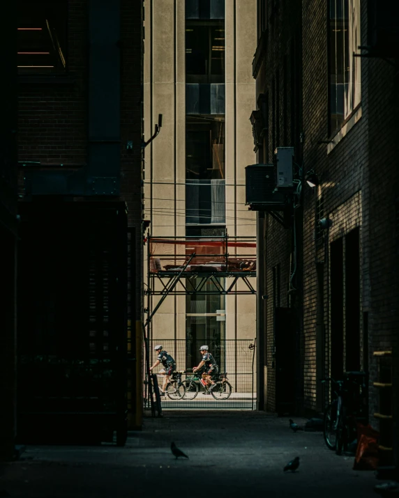 the view of people riding a bike through a gate in an alley