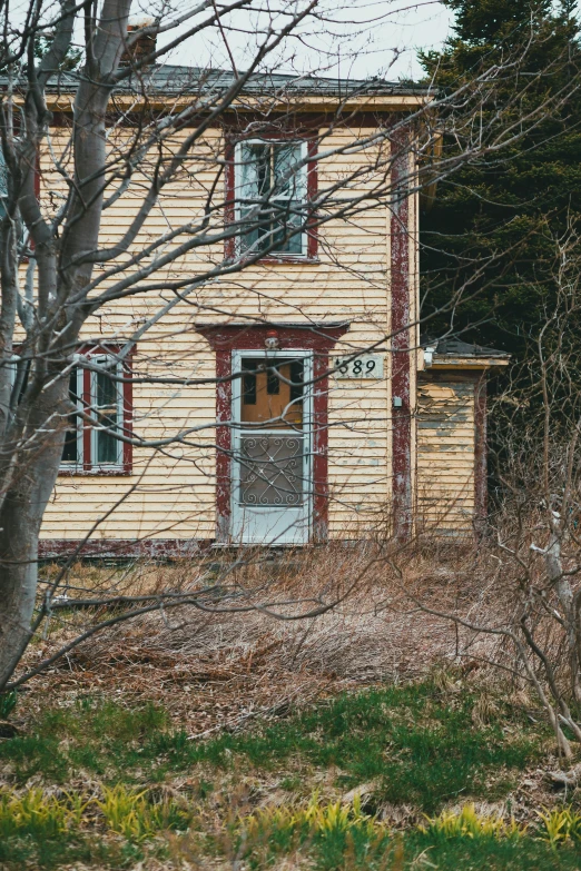 an old yellow house in a field with trees