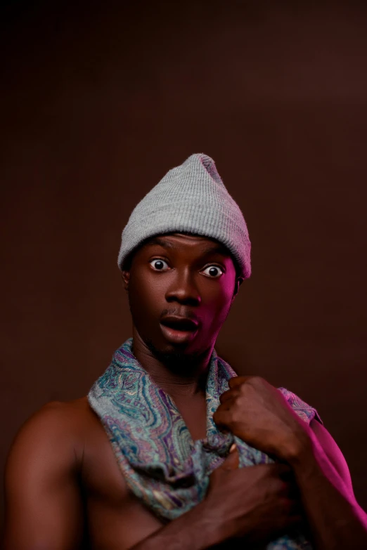 a man poses in his scarf, shirt, and cap