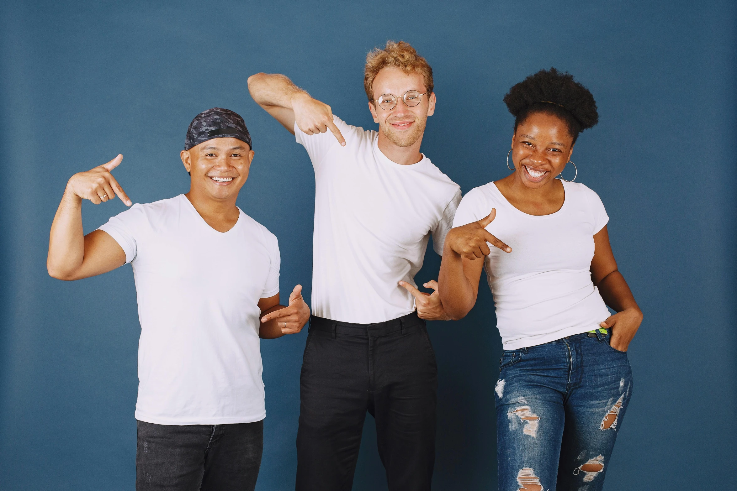 three people in white shirts are posing with one holding up his hand and giving a thumbs up