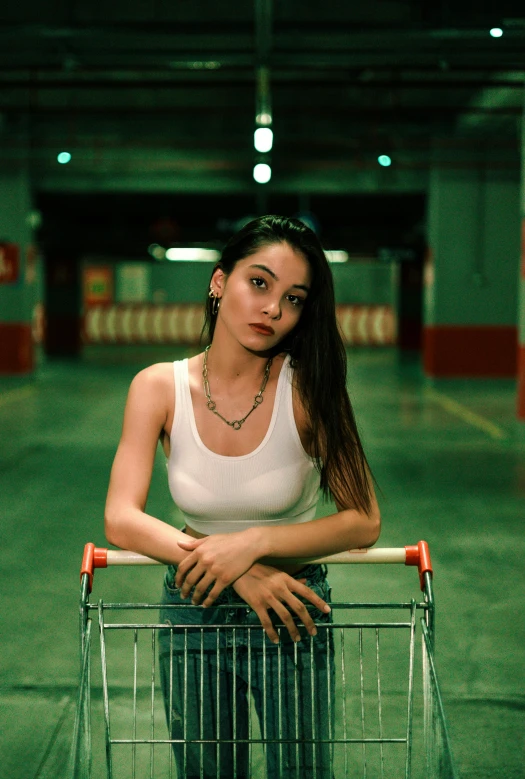 a woman stands inside of a shopping cart in an indoor parking lot