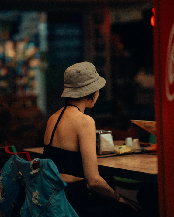a woman sits at a counter wearing a hat