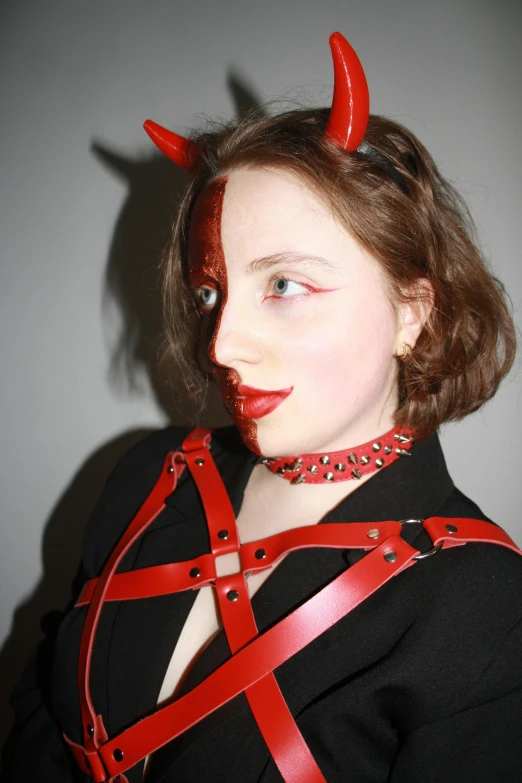 a girl with horns on her head wearing red harness