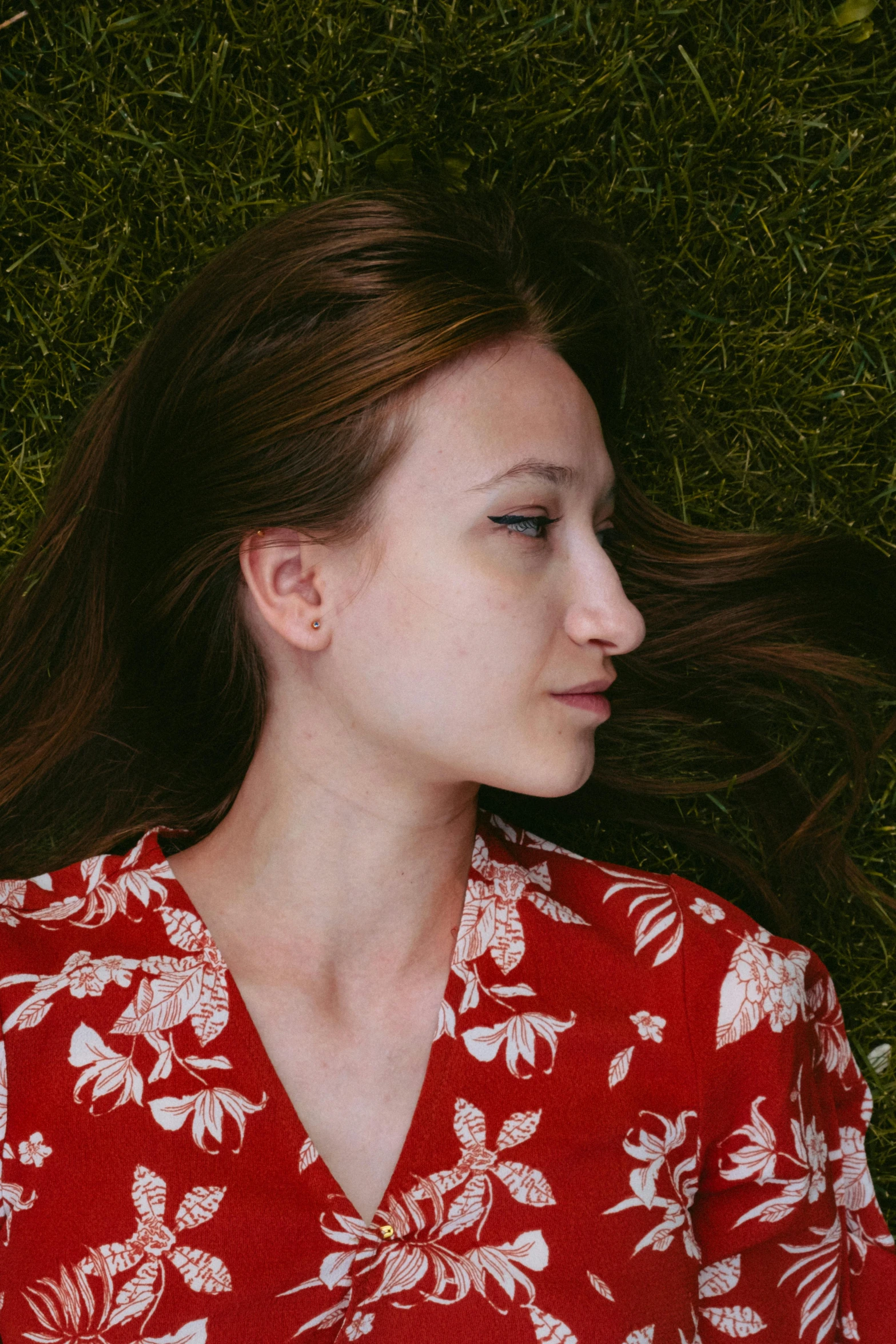 a young woman laying down in grass with her hair flying above her
