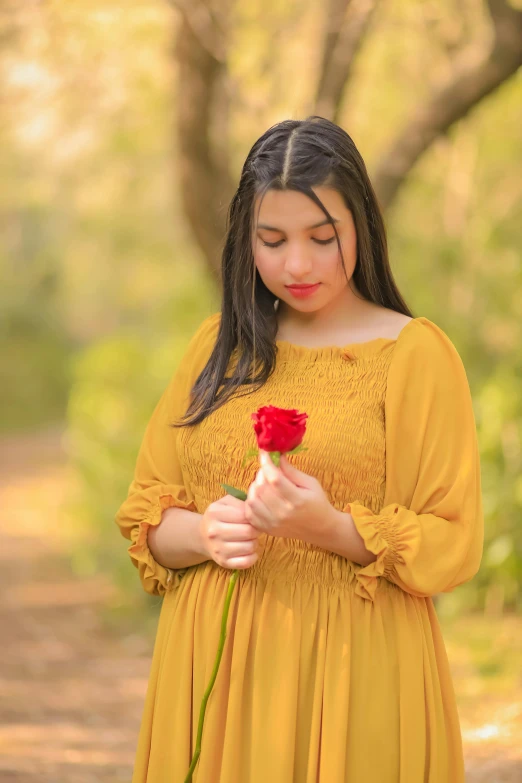 a girl in a yellow dress holding a rose