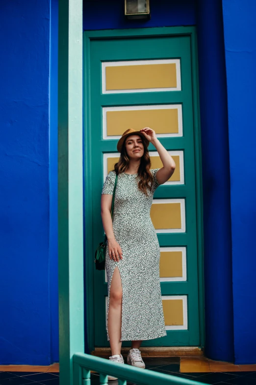 woman in dress leaning against green and blue wall