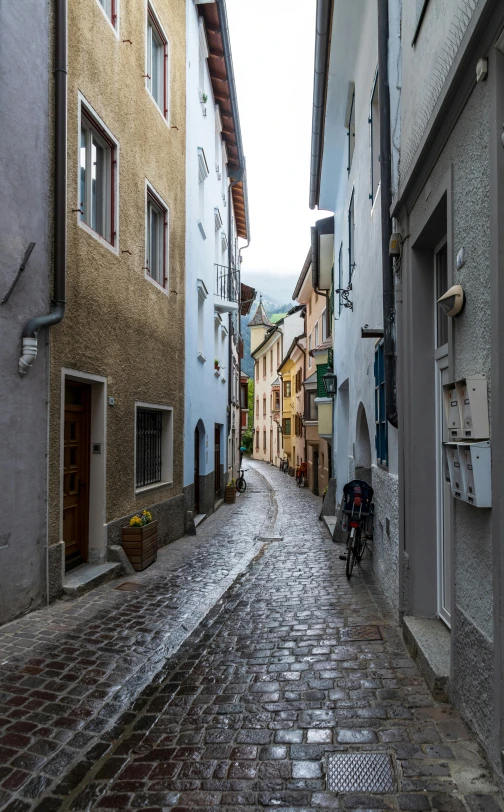 a narrow brick road and cobblestone buildings on both sides