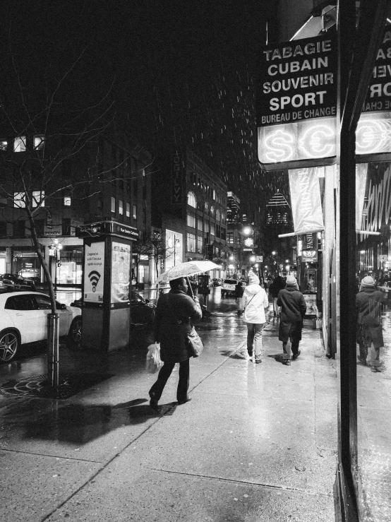 some people walking on a city street in the rain at night