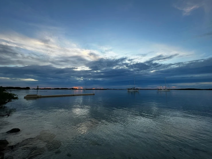 boats float on the still water in front of a cloudy sky