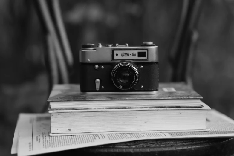 the camera is sitting on top of a pile of books