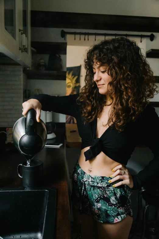 woman pouring water into her cup and wearing her bikini bottoms