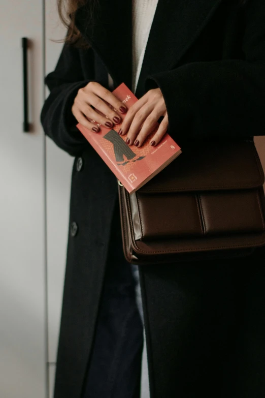 a woman in black jacket holding a brown book